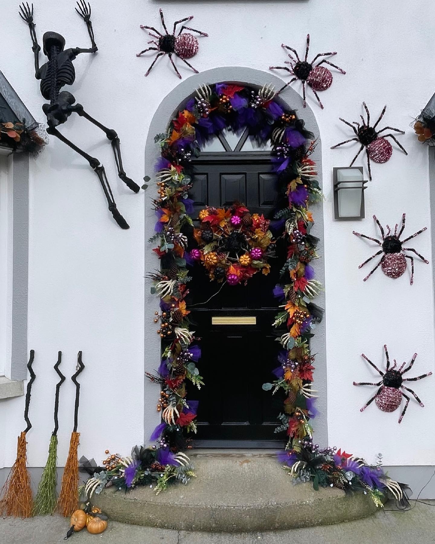 24. Spooky Spectacle Of Hanging Ghosts and Glowing Pumpkins on a Crimson Door