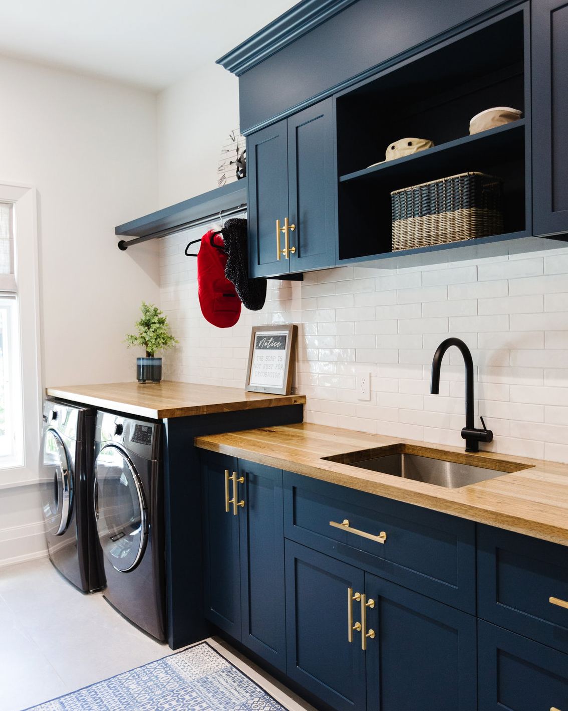 17. Sleek White Cabinets with Geometric Cutouts and Chrome Pulls Above a Vibrant Red Washer