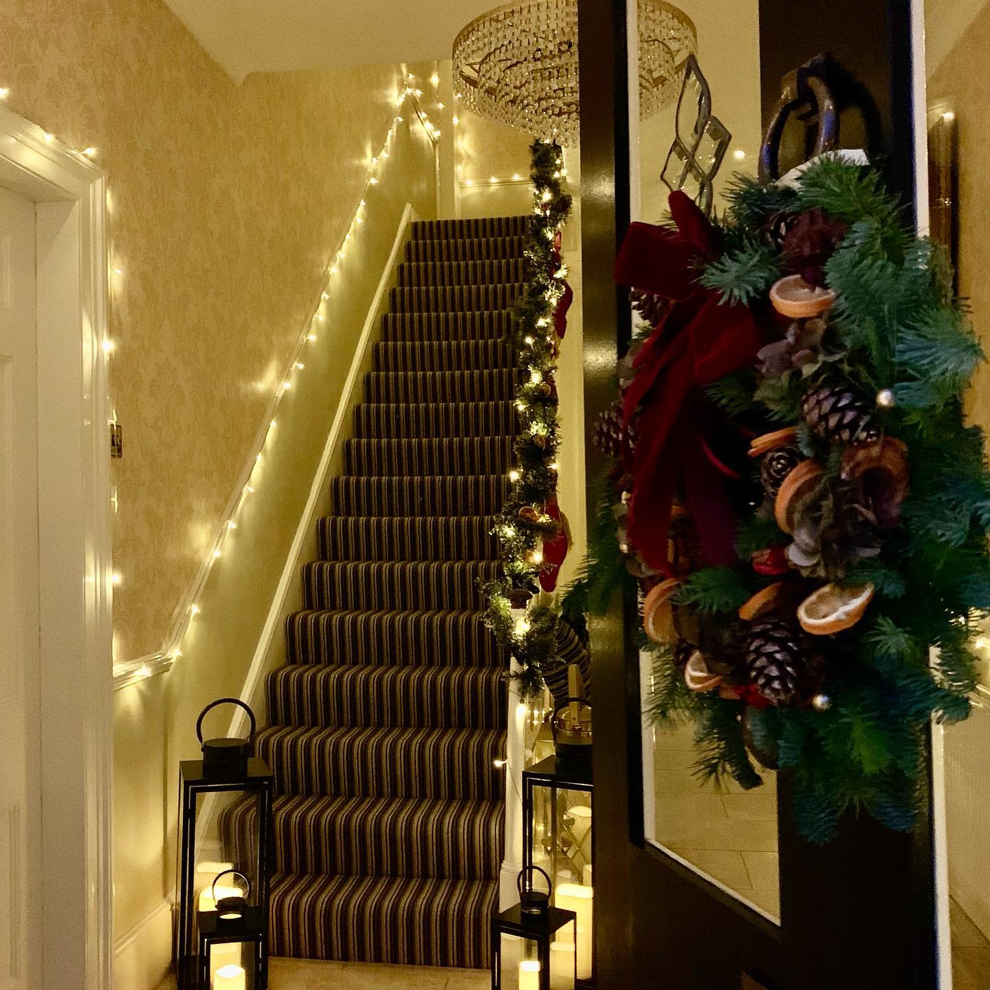 24. Shimmering Icicle Lights Draped Over a Crimson Garland with Golden Pinecones
