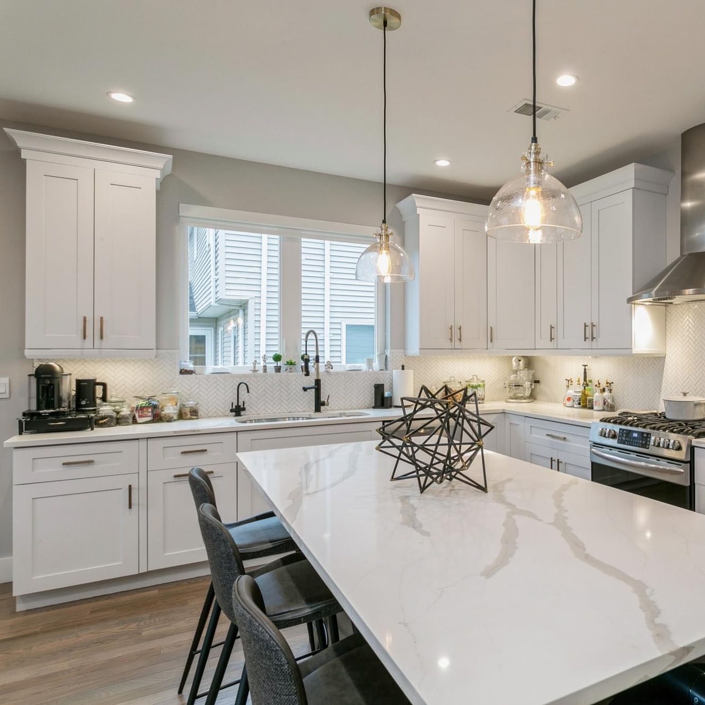 2. White Kitchen Cabinets with Geometric Black Inlay and Brass Hardware Accents