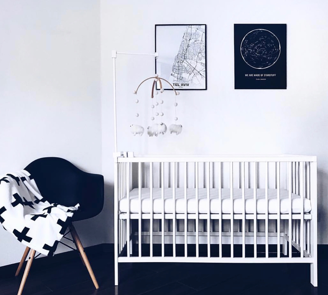 15. a Single White Crib Against a Bare Wall with a Monochrome Mobile