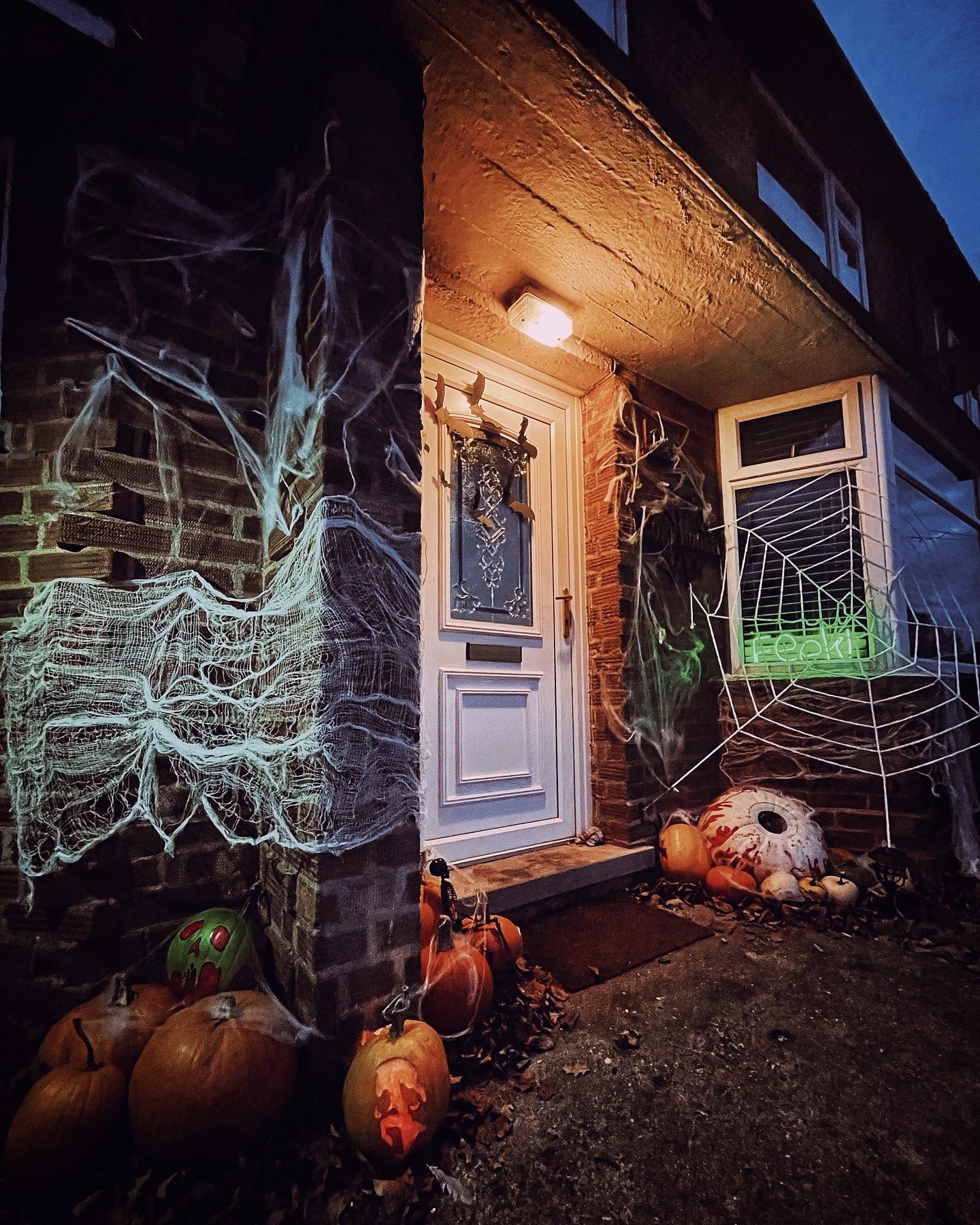 23. Spooky Silhouettes and Cobweb Canopy Over a Pumpkin Patch Door
